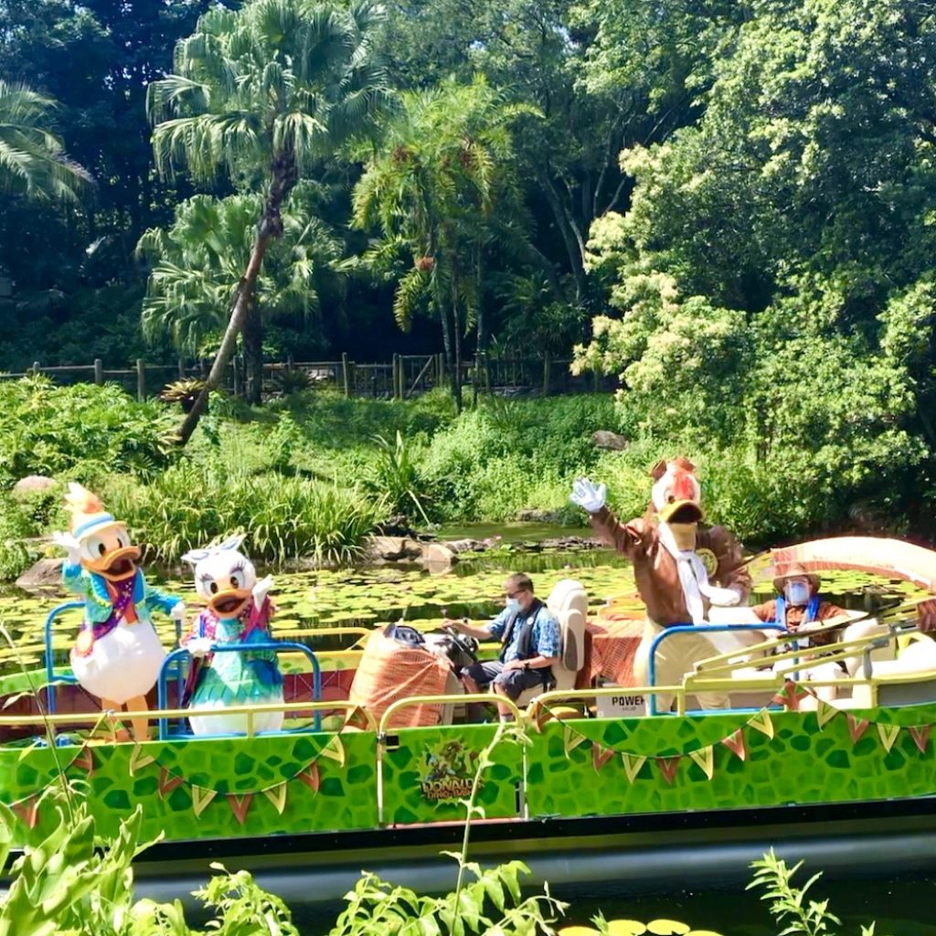 Characters floating by on boats at the Animal Kingdom. 