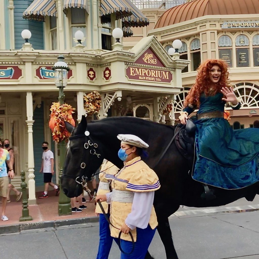 Merida riding by on a horse in the Magic Kingdom. 