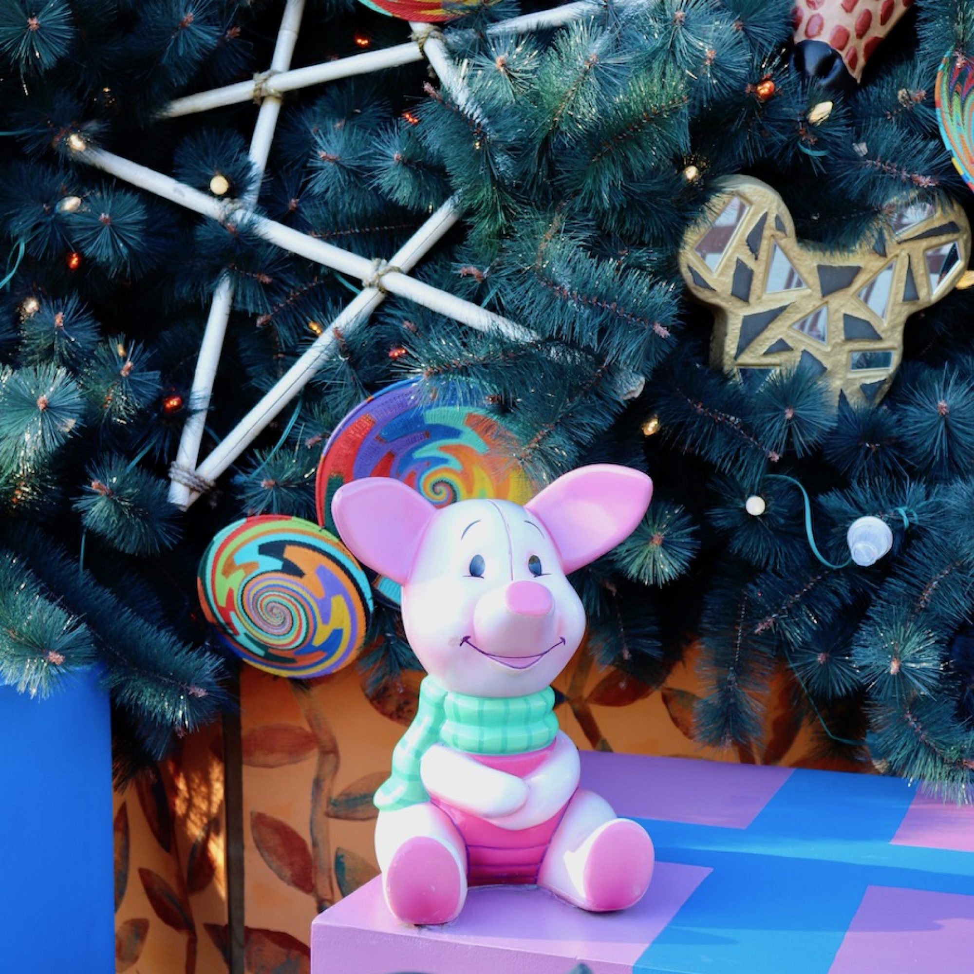 Piglet seated underneath Animal Kingdom's Christmas Tree.