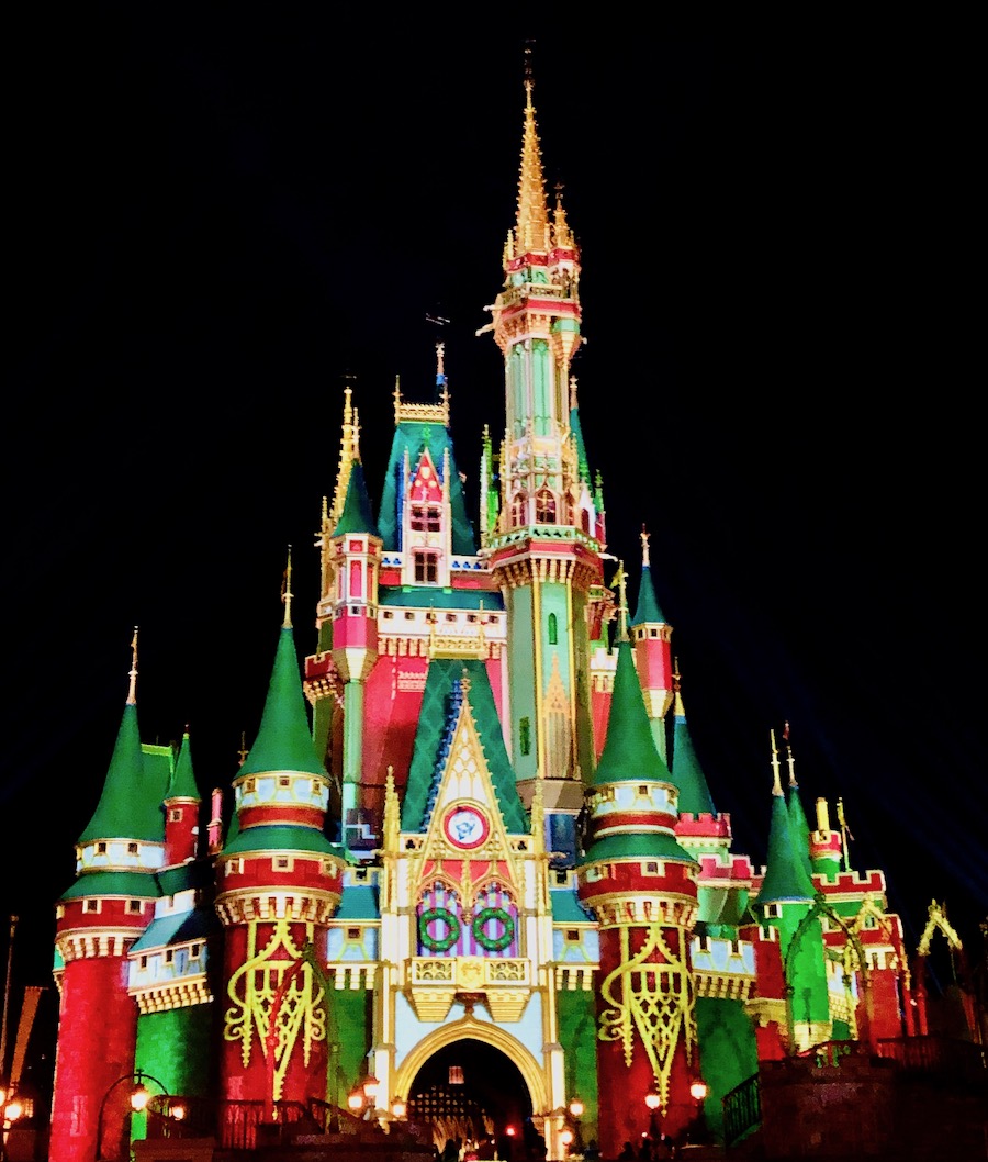 Festive red, green and gold holiday projection on Cinderella's Castle. 